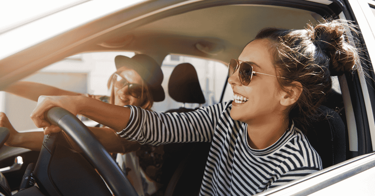 a woman happily driving in a car with her friend