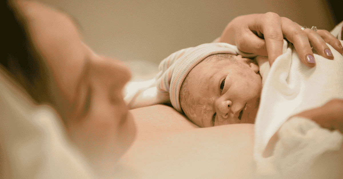 A mother holding her newborn baby on her chest.