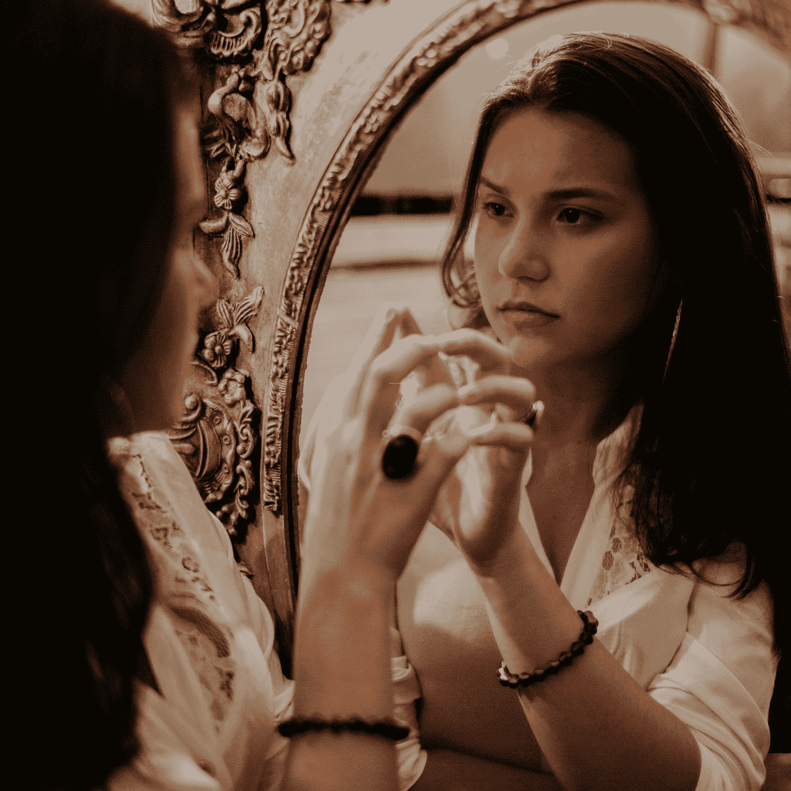  A woman looking at herself in a mirror with a pensive face and her finger tips touching the mirror. 