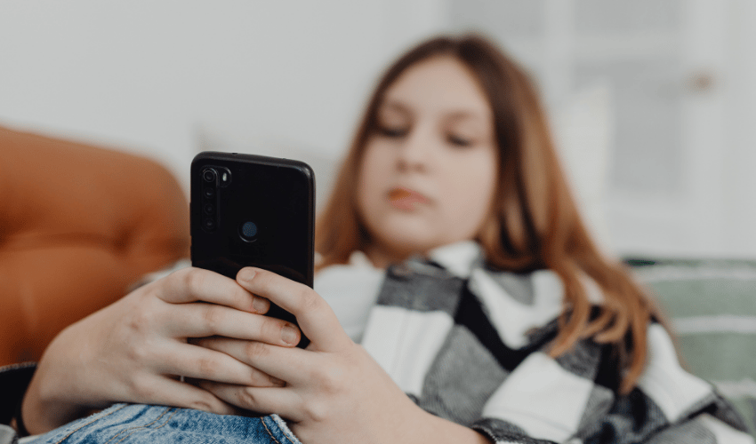 an image of a woman blurred out on her phone with the phone and her hands clearly visible reflection someone being in distraction mode