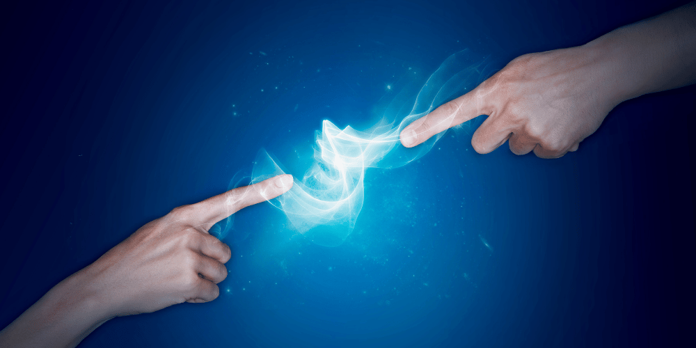 Two hands with the index fingers pointed outwards towards one another with a blue smokey energy field connecting them reflecting the energy of being a co-creator in your life. 